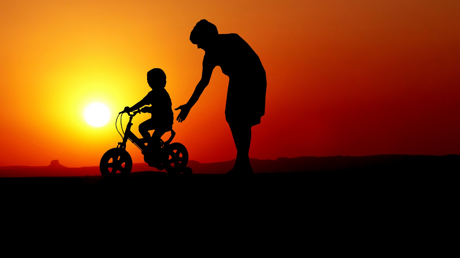 child on a bike cycling off into the sunset